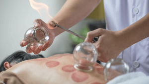 A woman is enjoying a holistic massage with a glass of water on her back. atma acupuncture