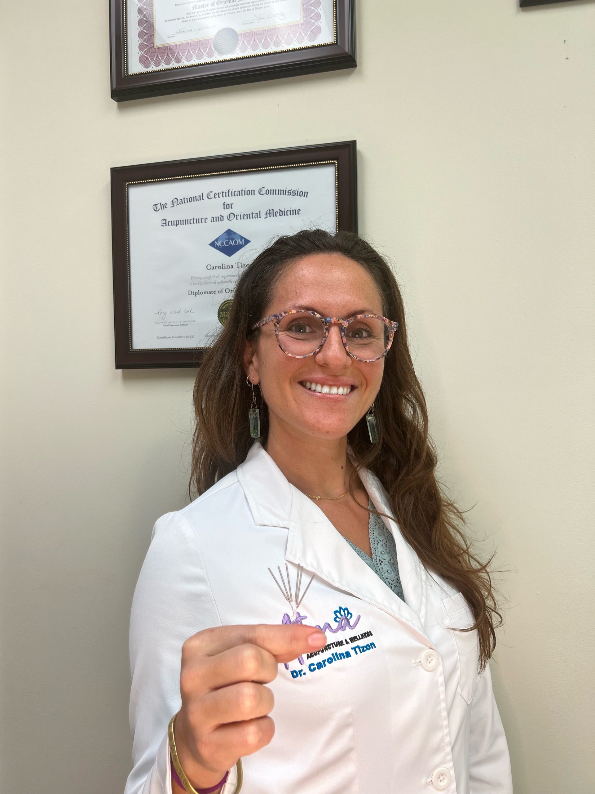 A woman in a white coat holding a pair of scissors, specializing in holistic therapy fort lauderdale. atma acupuncture