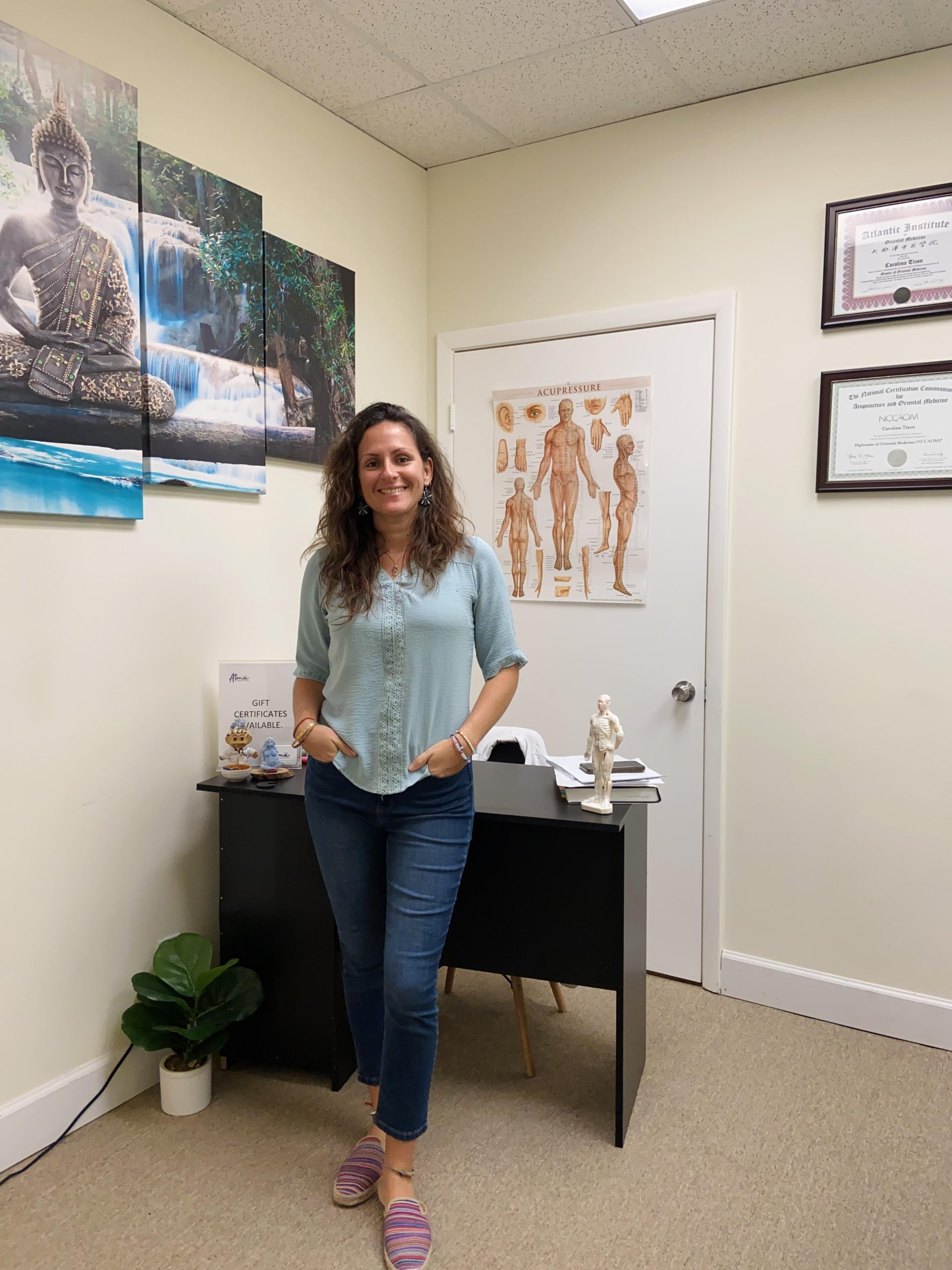 A woman in Florida standing in front of a desk in an office, exploring alternative medicine for fertility treatments. atma acupuncture
