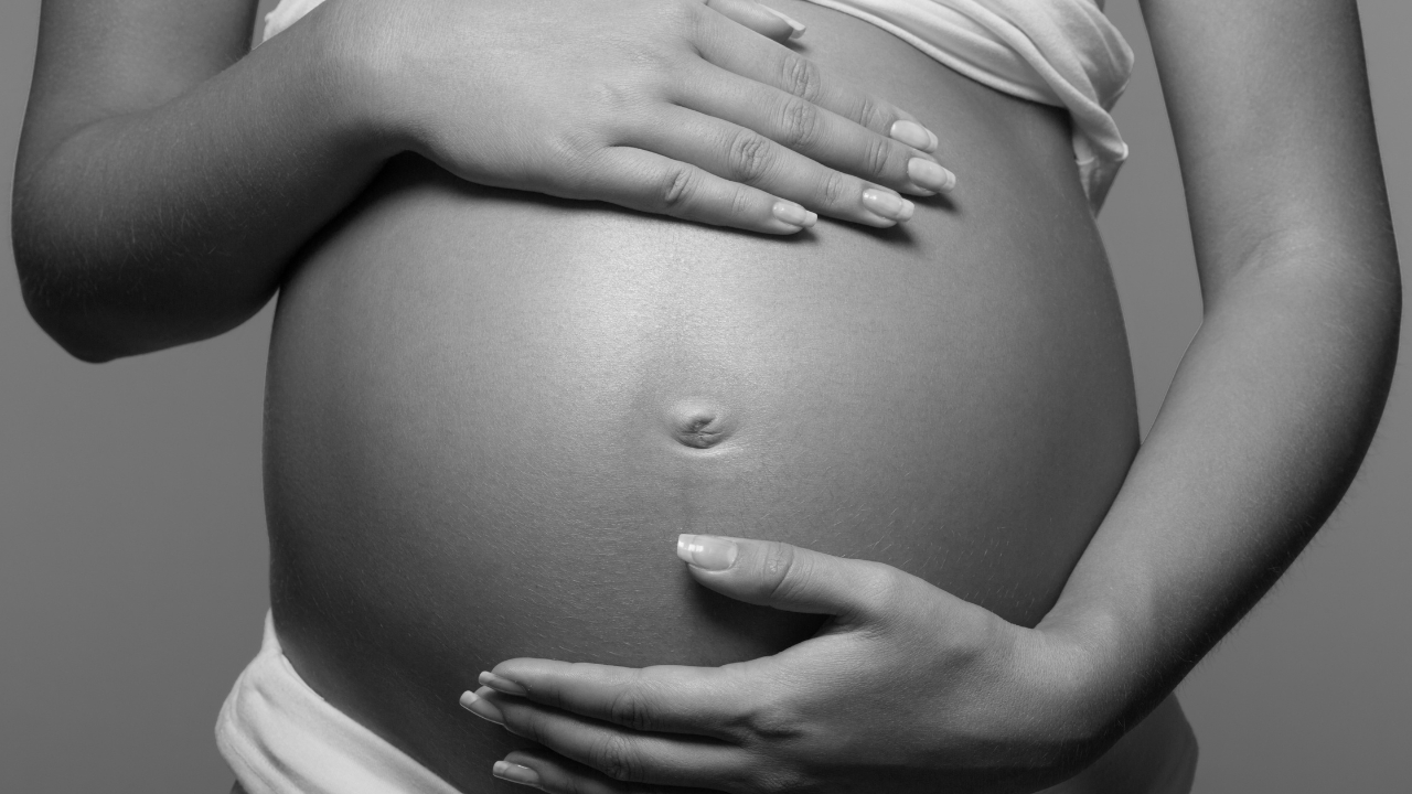 A pregnant woman's belly is shown in black and white, depicting the serene beauty of maternity. atma acupuncture