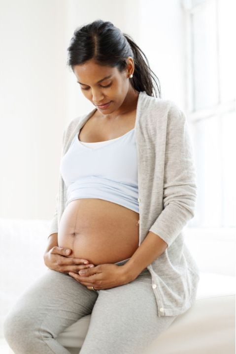 A pregnant woman sitting on a couch receiving holistic therapy in Fort Lauderdale. atma acupuncture