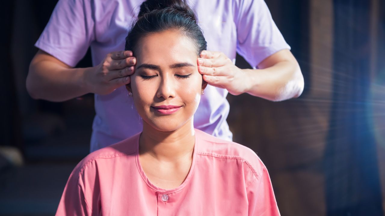 A woman is receiving a head massage by a therapist at a holistic therapy session. atma acupuncture