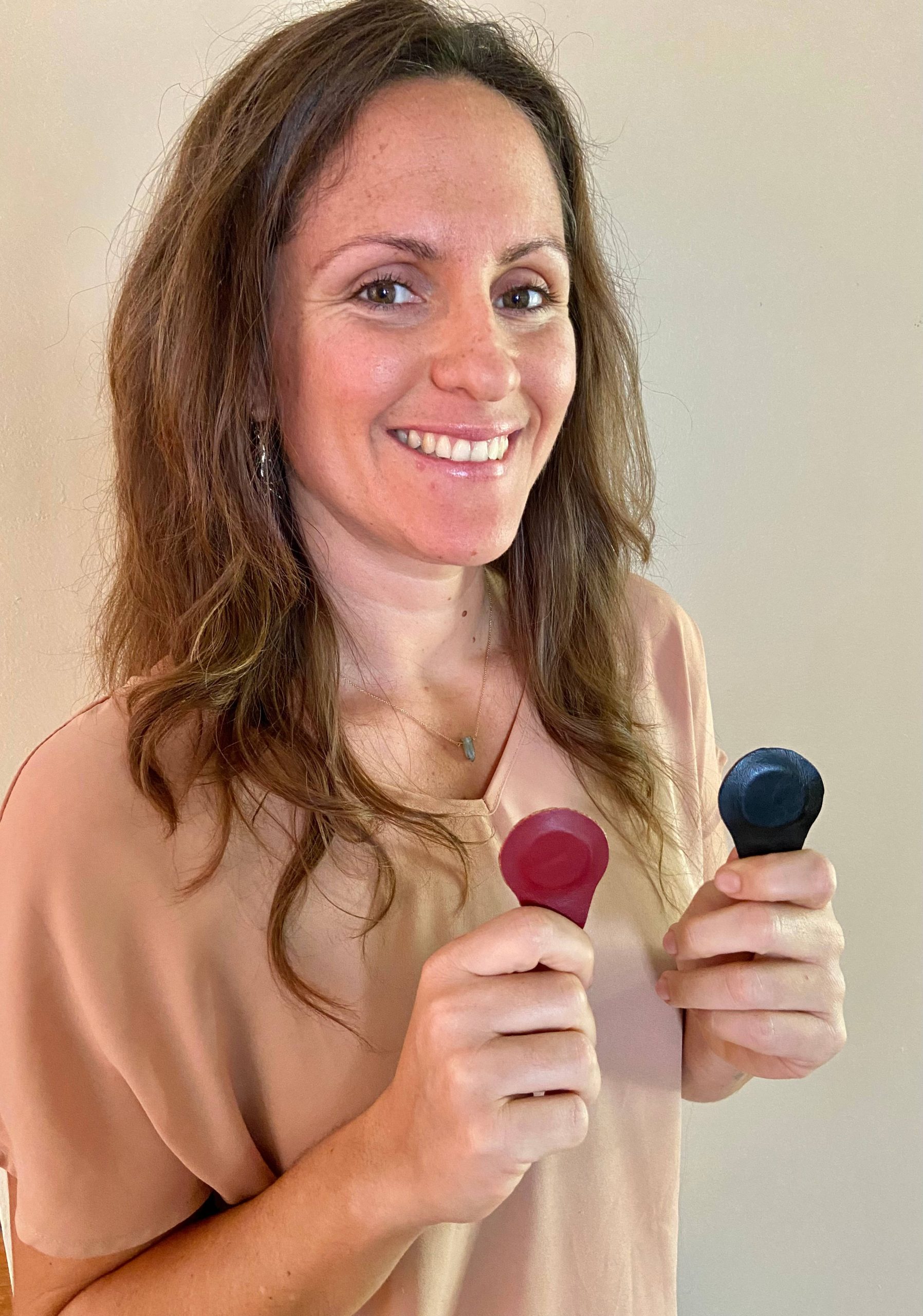A woman is holding a pair of earplugs for acupuncture fort lauderdale. atma acupuncture