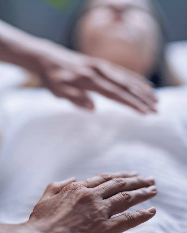 A woman receiving holistic therapy in Fort Lauderdale, with someone's hands gently touching her during the session. atma acupuncture