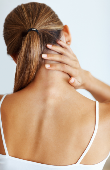 Person with a ponytail touching the back of their neck, wearing a white tank top. atma acupuncture
