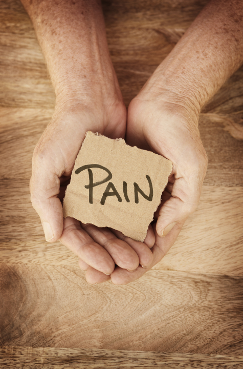 Hands holding a piece of cardboard with the word "PAIN" written on it. atma acupuncture